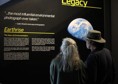 Two visitors look at a display featuring the famous Earthrise image